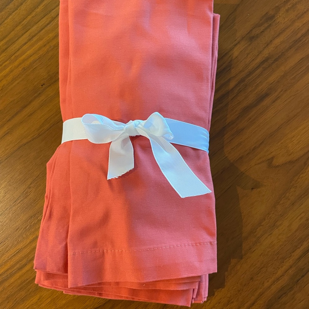 Eight Crate & Barrel Coral-colored cloth napkins.